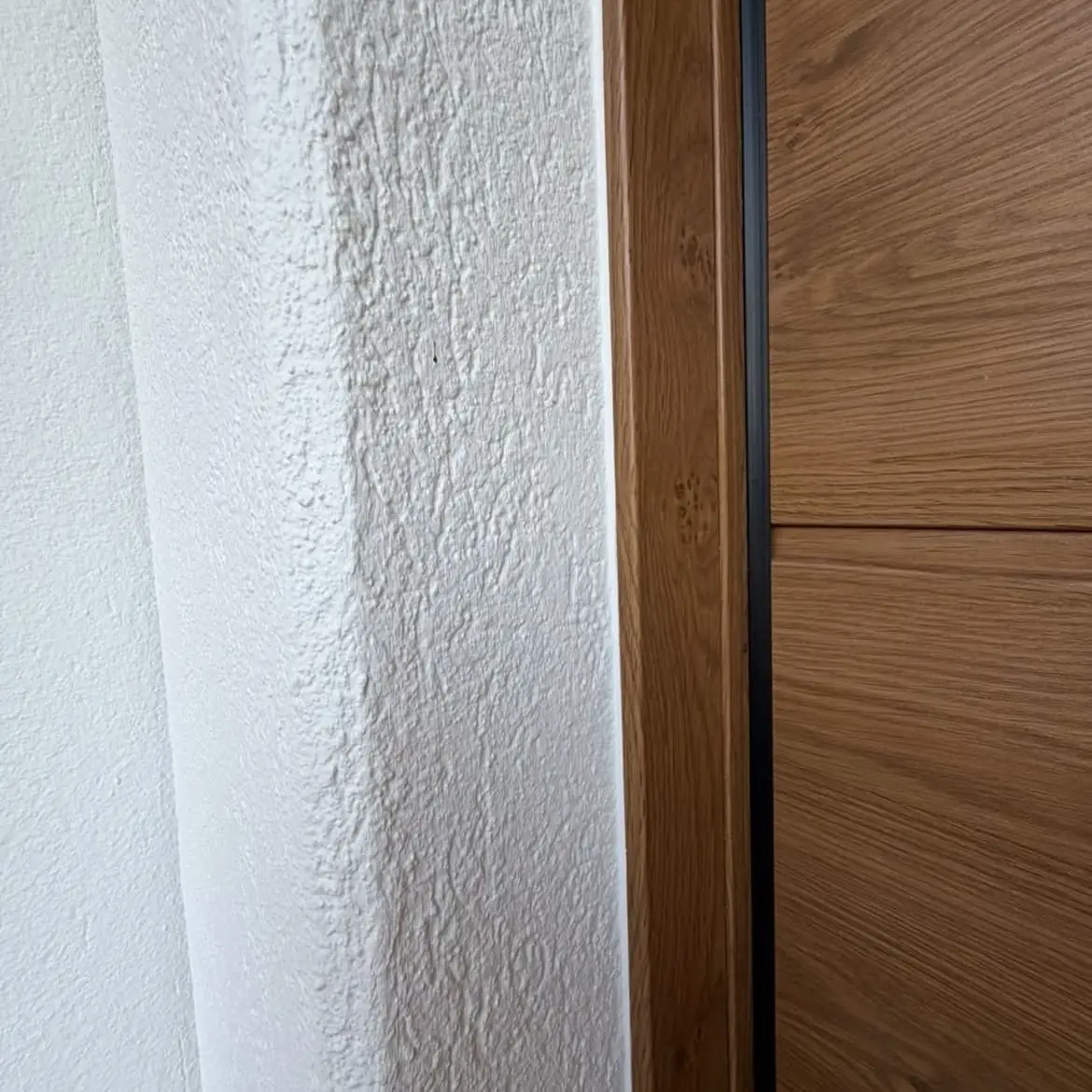 Encadrement de porte en bois contre un crépi blanc