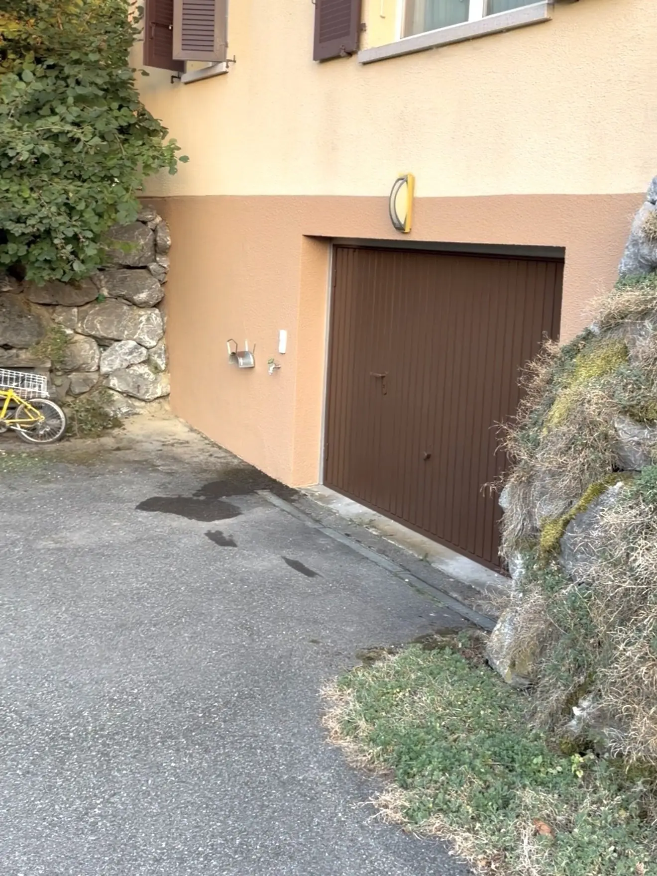 Façade crépie avec volets et porte de garage repeints en brun